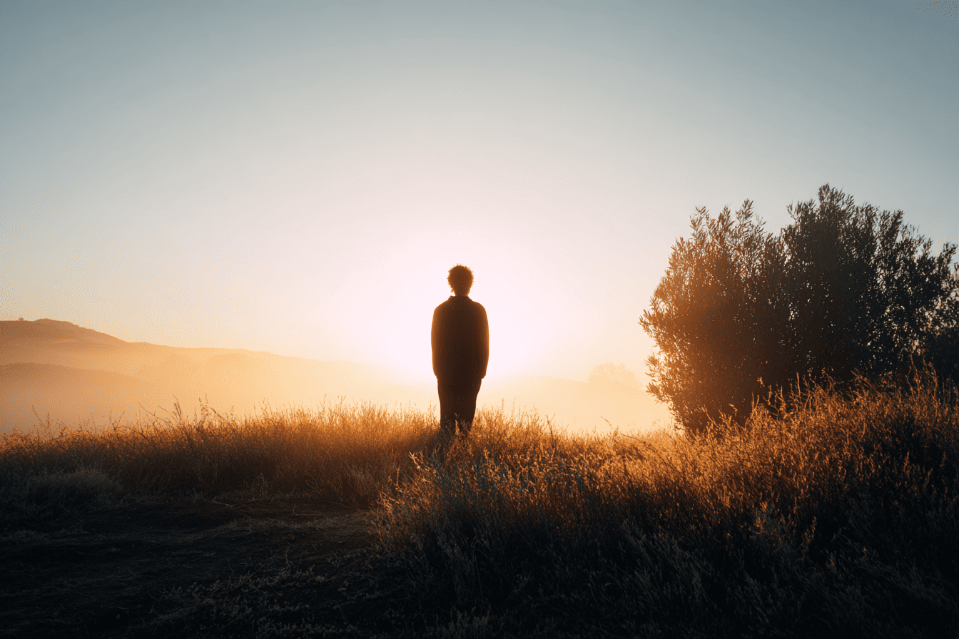 Wat is een transformatie coach? Deze persoon staat stil bij zonsopkomst in de natuur staat en symbool staat voor innerlijke rust en persoonlijke transformatie