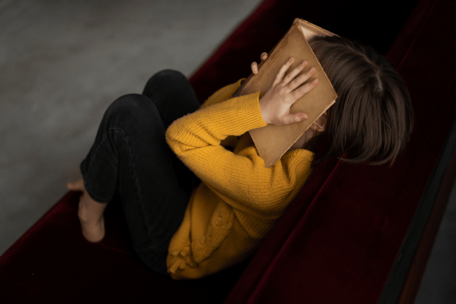 Boeken sombere vrouw op bank gele trui