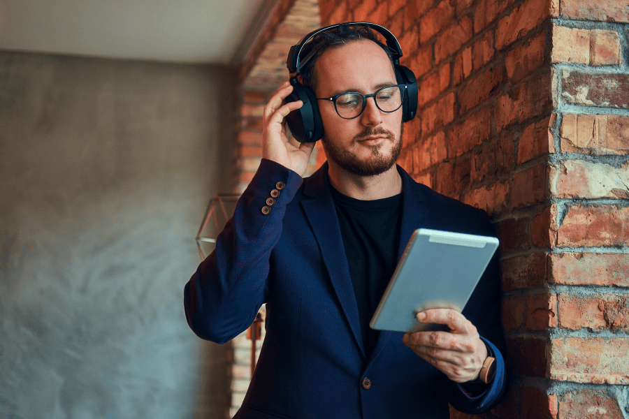 man muur ipad koptelefoon bril pak podcast over ondernemen